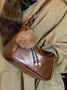 Sac bandoulière marron foncé vintage avec charme sur mannequin en trench olive
