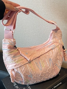 Pink quilted hobo crossbody bag with colorful wavy embroidery and wide shoulder strap