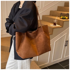 Macro side view of a large brown suede tote bag showing texture and strap details