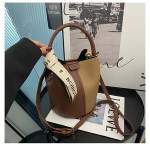 Detail of a two-tone bucket bag with lychee grain leather and fashion ribbon handle