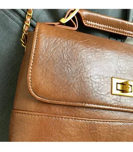 Gros plan sur la texture du cuir marron vintage avec fermoir rotatif doré et chaîne