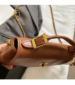 Détail du sac rétro en cuir marron avec boucle dorée et décoration latérale en perles