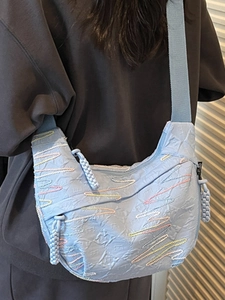 Light blue pleated crescent crossbody bag with colorful wavy embroidery and wide fabric strap