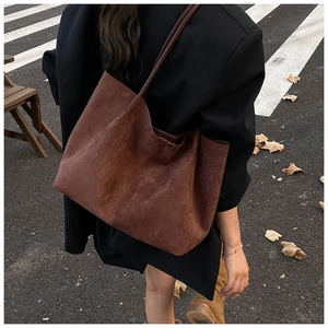 Macro detail of the soft suede texture and natural drapes on a dark brown tote bag