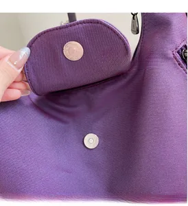 Macro shot of purple textured fabric and round metallic magnetic clasp on tote bag