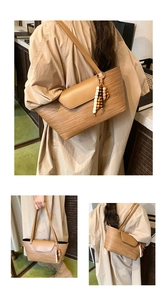 Dettaglio di una borsa tote intrecciata marrone con ciondolo in legno e spalline in pelle