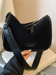 Minimalistische schwarze Wildleder Umhängetasche mit Doppelreißverschluss in der Hand