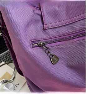 Detail of purple textured tote bag featuring a kangaroo-shaped metal zipper and smooth closure