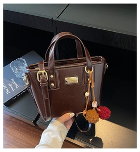 Dettaglio della borsa a secchiello in pelle PU marrone scuro con placca in metallo dorato