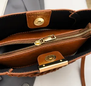 Detail view of brown PU bucket bag showing smooth gold zippers and magnetic closures