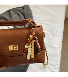 Gros plan d'un sac en cuir marron avec fermoir doré et pendentif en perles de bois