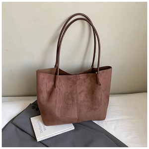 Detailed close-up of brown suede tote bag with vertical stitching and slim handles