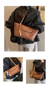 Dettaglio della trama intrecciata su borsa marrone con nappa decorativa in legno