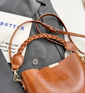 Close-up of brown PU leather bucket bag featuring woven handle and gold metal lock