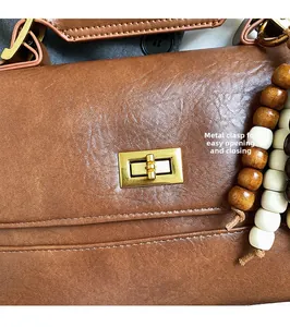Gros plan d'un sac en cuir marron avec fermoir tournant doré et gland en perles de bois