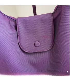Detailed macro view of purple pleated fabric texture with magnetic snap button on tote bag