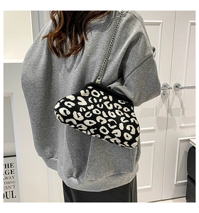 Détail du sac nuage en tricot imprimé léopard avec chaîne argentée porté par le mannequin
