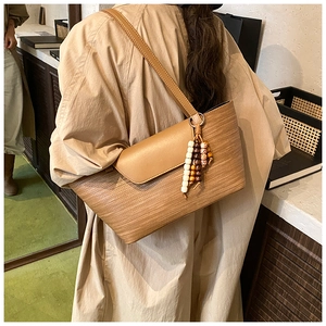 Dettaglio borsa tote intrecciata a mano con ciondolo in legno e spalline sottili
