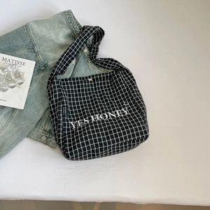 Detail der karierten Canvas-Tragetasche mit YES HONEY Stickerei und Denim-Jacke