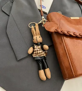 Knitted bunny charm in houndstooth vest attached to a premium brown leather bucket bag