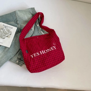 Detail der rot-schwarz karierten Canvas-Einkaufstasche mit YES HONEY Stickerei und Lächeln
