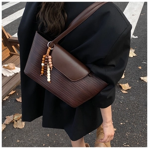 Dettaglio della borsa tote intrecciata marrone scuro con ciondolo di perle in autunno