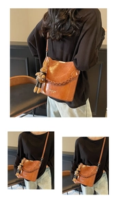 Detail of a brown PU leather bucket bag featuring a woven strap and a cute rabbit charm