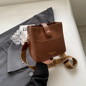 Vue détaillée du sac seau en cuir marron avec large bandoulière en tissu imprimé