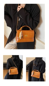 Détail du sac bandoulière marron caramel avec fermoir rotatif et breloque à pompon coloré