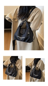 Detail showing the NUONUODAISHU 1997 logo and metallic zipper on a black nylon tote