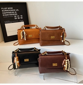 Détail de sacs bandoulière vintage en quatre couleurs avec breloques et chaînes en métal