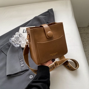 Détail du sac seau vintage marron avec texture litchi et bandoulière tissée large
