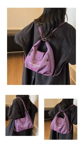 Detail view of purple nylon tote bag with flap closure and white lettering on black coat