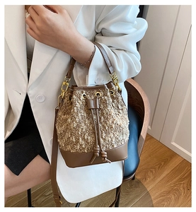 Detailed view of brown tweed bucket bag with leather strap on model in white blazer