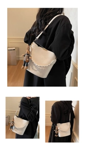 Detail view of white PU bucket bag with woven handle and cute plush rabbit charm accessory
