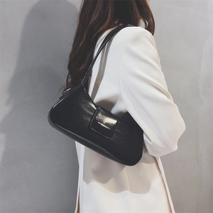 Detail of elegant black glossy leather hobo bag showing moon-shaped curve and magnetic flap