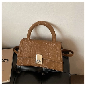 Detail of dark brown snakeskin textured hourglass handbag with silver metal twist lock