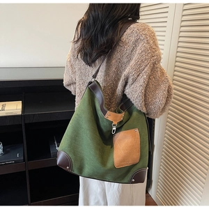 Detail view of large green suede hobo bag with brown leather trim and rivet pocket
