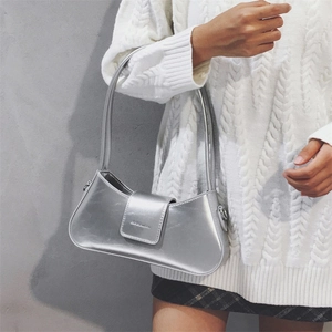 Detail of silver metallic baguette bag worn over the shoulder with a white knit sweater