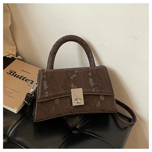 Detailed view of dark brown snakeskin texture and silver twist lock on the hourglass bag