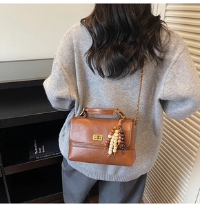Détail du sac bandoulière marron vintage avec fermoir doré et pampille de perles colorées