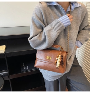 Détail du sac bandoulière marron vintage avec boucle dorée et breloque en perles colorées