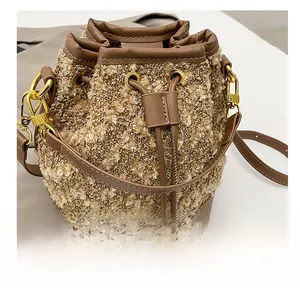 Detail showing the brown knit bucket bag with leather drawstring and gold metal hooks