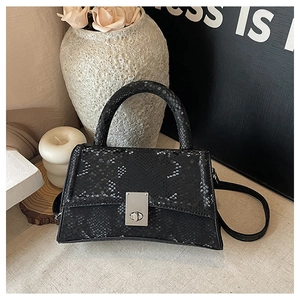 Detail of black snake pattern texture on leather handbag with silver turn-lock closure