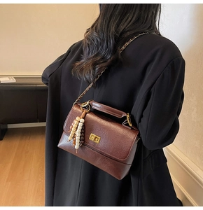 Détail du sac bandoulière marron rétro avec pompon perlé et fermoir doré rotatif