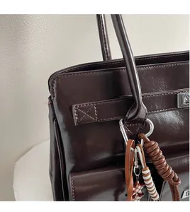 Nahaufnahme der dunkelbraunen Leder-Tote-Bag mit silbernem Drehverschluss und Anhänger