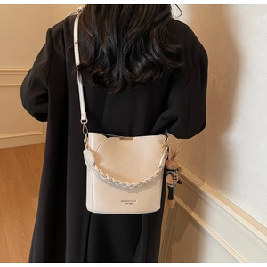Detail of cream PU leather bucket bag with woven handle and cute plush bunny charm