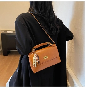 Détail du sac en cuir marron avec boucle dorée et breloque en perles colorées