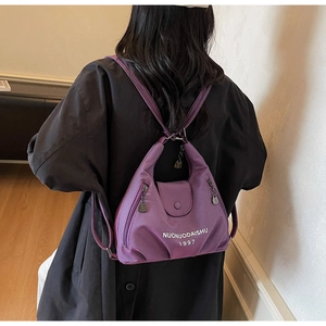 Close-up of a purple nylon tote bag featuring white text branding and functional side pocket