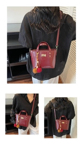 Dettagli della borsa a secchiello bordeaux in vernice con hardware dorato e charm a pompon